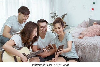 Group Of Asian Friends Having Party, Playing Guitar And Singing Together With Fun At Home. Lifestyle Concept.