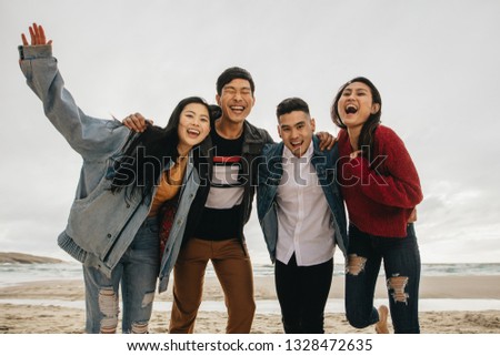 Group of asian friends on the seashore. Young people having great time together at the beach.