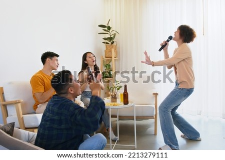 Group of Asian friends playing karaoke and sing a song at home together