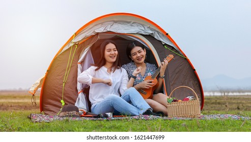 A Group Of Asian Friends Playing Ukelele And Spending Time Making A Picnic In The Summer Holidays.They Are Happy And Have Fun On Holidays.