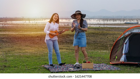 A Group Of Asian Friends Playing Ukelele And Spending Time Making A Picnic In The Summer Holidays.They Are Happy And Have Fun On Holidays.