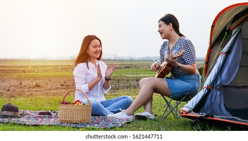 A Group Of Asian Friends Playing Ukelele And Spending Time Making A Picnic In The Summer Holidays.They Are Happy And Have Fun On Holidays.