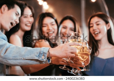 Group of Asian friends smiling and toasting glass of wine together to celebration at the party. Congratulations on success achievement. People hangout on weekend night.