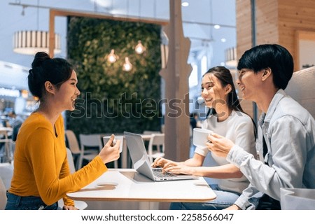 Group of Asian friends talking and using laptop computer in restaurant. Attractive young man and woman people feel happy and relax, having fun hangout indoors enjoy meeting reunion in cafe cafetaria.