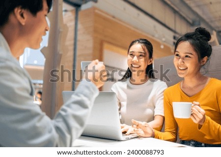 Group of Asian friends talking and using laptop computer in restaurant. Attractive young man and woman people feel happy and relax, having fun hangout indoors enjoy meeting reunion in cafe cafetaria.