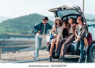 Group of Asian generation z people friends sitting on car trunk looking beautiful nature of countryside. Man and woman friendship enjoy and fun outdoor lifestyle road trip on summer holiday vacation. - Powered by Shutterstock