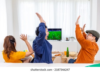 Group Of Asian Man And Woman Friends Watching Soccer Games World Cup Competition On Television With Eating Snack Together At Home. Sport Fans People Shouting And Celebrating Sport Team Victory Match.