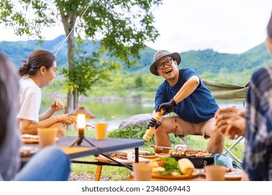 Group of Asian man and woman friends having dinner eating food and drinking beer together during camping together. People enjoy outdoor lifestyle travel nature hiking and camping on summer vacation. - Powered by Shutterstock