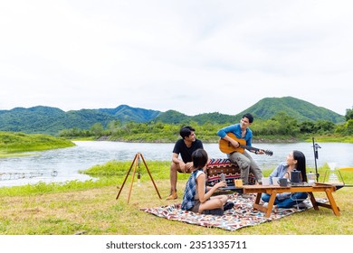 Group of Asian man and woman friends singing and playing guitar during having breakfast by the lake together. People enjoy and fun outdoor lifestyle travel nature camping on summer holiday vacation. - Powered by Shutterstock