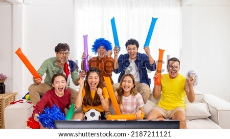 Group of Asian man and woman friends watching soccer games world cup competition on television with eating snack together at home. Sport fans people shouting and celebrating sport team victory match.