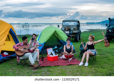 Group Asian Of Man And Women Have Friendship Enjoy Camping For Picnic And Barbecue At Lake With Tents On Background; Travel Concept And Happy Familly.