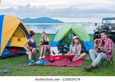 Group Asian Of Man And Women Have Friendship Enjoy Camping For Picnic And Barbecue At Lake With Tents On Background; Travel Concept And Happy Familly.