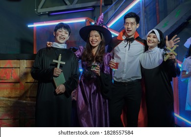 A group of Asian men and women wearing as vampire, witch, dead nun, pastor having Fun at Party in Nightclub. Celebration of Halloween