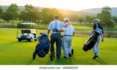 Group Of Asian People Businessman And Senior CEO Enjoy Outdoor Sport  Golfing Together At Country Club. Healthy Men Golfer Holding Golf Bag Walking On Fairway With Talking Together At Summer Sunset