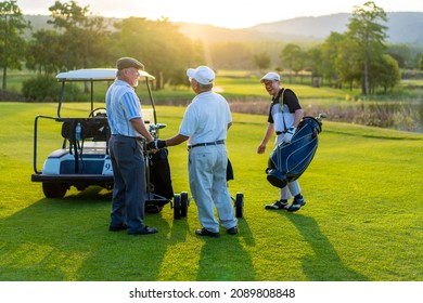 Group Of Asian People Businessman And Senior CEO Enjoy Outdoor Sport Lifestyle Golfing Together At Golf Country Club. Healthy Men Golfer Shaking Hand After Finish Game On Golf Course At Summer Sunset