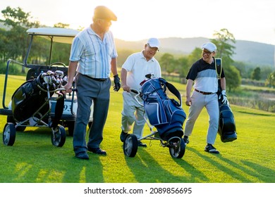 Group Of Asian People Businessman And Senior CEO Enjoy Outdoor Sport  Golfing Together At Country Club. Healthy Men Golfer Holding Golf Bag Walking On Fairway With Talking Together At Summer Sunset