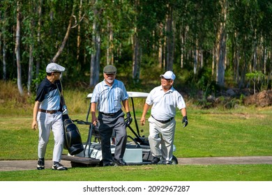 Group Of Asian People Businessman And Senior CEO Enjoy Outdoor Sport Golfing Together At Country Club. Healthy Men Golfer Holding Golf Bag Walking On Fairway With Talking Together On Summer Vacation