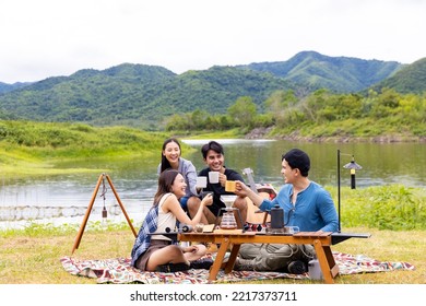 Group of Asian people enjoy and fun outdoor lifestyle hiking and camping together on summer travel vacation. Man and woman friends having breakfast drinking brewed coffee near the tent in the morning. - Powered by Shutterstock