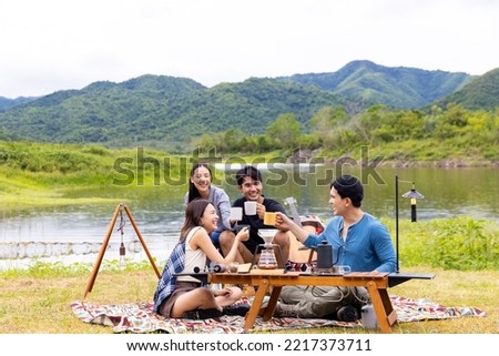 Group of Asian people enjoy and fun outdoor lifestyle hiking and camping together on summer travel vacation. Man and woman friends having breakfast drinking brewed coffee near the tent in the morning.