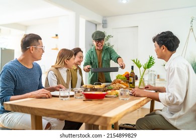 Group Of Asian People Friends Enjoy Dinner Party Eating Food And Drinking Wine On The Table With Talking Together At Home. Happy Man And Woman Reunion Dinner Meeting Celebration On Holiday Vacation