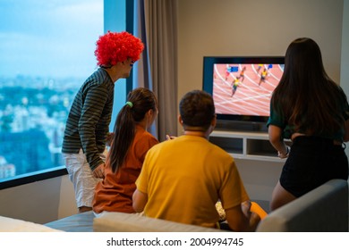 Group Of Asian People Friends Sit On Sofa Watching And Cheering Sports Games Competition On TV Together At Home. Excited Man And Woman Sport Fans Celebrate Sport Team Victory In National Sports Match