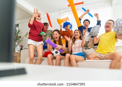 Group Of Asian People Friends Sit On Sofa Watching And Cheering Soccer Games Competition On TV Together At Home. Happy Man And Woman Sport Fans Shouting And Celebrating Sport Team Victory Sports Match