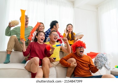 Group of Asian people friends sit on sofa watching and cheering soccer games competition on TV together at home. Happy man and woman sport fans shouting and celebrating sport team victory sports match - Powered by Shutterstock
