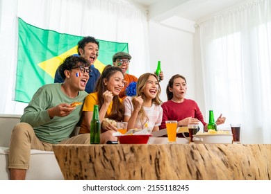 Group Of Asian People Friends Sit On Sofa Watching Soccer Games Competition On TV With Eating Food Together At Home. Man And Woman Sport Fans Shouting And Celebrating Sport Team Victory Sports Match