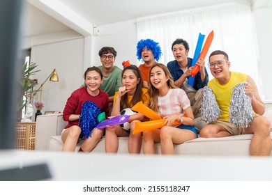 Group Of Asian People Friends Sit On Sofa Watching And Cheering Soccer Games Competition On TV Together At Home. Happy Man And Woman Sport Fans Shouting And Celebrating Sport Team Victory Sports Match