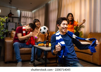 Group of Asian people friends sit on sofa watching and cheering football or soccer games competition on TV together at home.Happy man and woman sport fans celebrating sport team victory sports match - Powered by Shutterstock