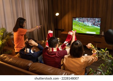 Group of Asian people friends sit on sofa watching and cheering football or soccer games competition on TV together at home.Happy man and woman sport fans celebrating sport team victory sports match - Powered by Shutterstock