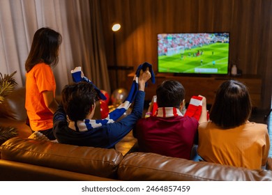 Group of Asian people friends sit on sofa watching and cheering football or soccer games competition on TV together at home.Happy man and woman sport fans celebrating sport team victory sports match - Powered by Shutterstock