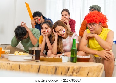 Group Of Asian People Friends Sitting On Sofa And Watching Soccer Games Competition On Television Together At Home. Man And Woman Sport Team Fans Cheering Football Sport Match On TV In Living Room