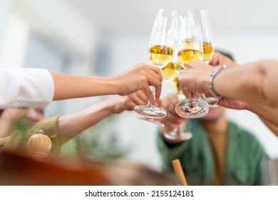 Group Of Asian People Friends Toasting Wine Glasses While Having Dinner On Dining Table With Talking Together At Home. Happy Man And Woman Reunion Dinner Meeting Celebration On Holiday Vacation