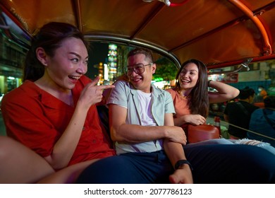 Group Of Asian People Tourist Traveling In Bangkok City By Tuk Tuk Taxi Car Together At Night. Male And Female Friends Enjoy And Having Fun Outdoor Lifestyle Travel City Street Nightlife In Thailand.