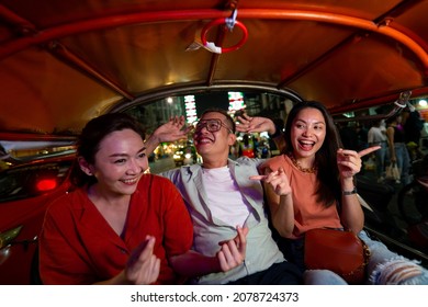 Group of Asian people tourist traveling in Bangkok city by Tuk Tuk taxi car together at night. Male and female friends enjoy and having fun outdoor lifestyle travel city street nightlife in Thailand.