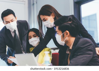 Group of Asian people working and brainstorming at desk together. man and woman wearing protective mask talking and looking computer laptop. keep social distancing and new normal at office concept - Shutterstock ID 1913216836