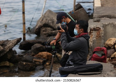 A Group Of Asian Photographers Hunting Landscape Photos Together With DSLR Camera In Hand And Tripod In Surabaya - Indonesia On April 29, 2022