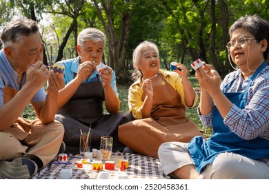 A group of Asian senior people enjoy painting cactus pots and recreational activity or therapy outdoors together  at an elderly healthcare center, Lifestyle concepts about seniority - Powered by Shutterstock