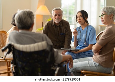 Group Of Asian Senior People Listening To Young Nurse. Psychological Support Group For Elderly And Lonely People In A Community Centre. Group Therapy In Session Sitting In A Circle In A Nursing Home.