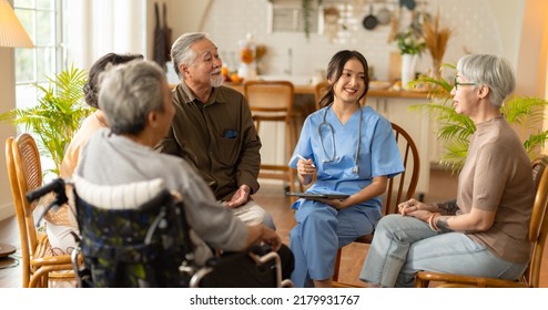 Group Of Asian Senior People Listening To Young Nurse. Psychological Support Group For Elderly And Lonely People In A Community Centre. Group Therapy In Session Sitting In A Circle In A Nursing Home.