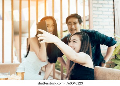 Group Of Asian Smiling Friends Taking Funny Selfie In Restaurant.