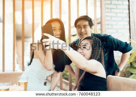 Group of asian smiling friends taking funny selfie in restaurant.