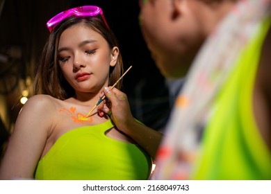 Group of Asian woman friends enjoy and fun outdoor lifestyle do body painting with celebrating and dancing together at full moon night party at koh phangan island beach in Thailand on summer vacation. - Powered by Shutterstock