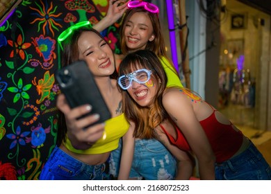 Group of Asian woman friends using mobile phone taking selfie together while having fun celebrating and dancing at full moon party festival at koh phangan island beach in Thailand on summer vacation - Powered by Shutterstock