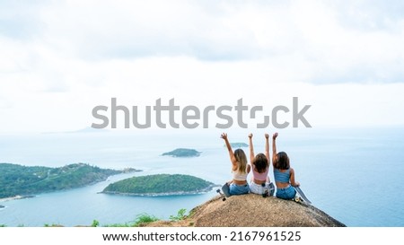 Group of Asian woman sitting skater on mountain peak while hiking at tropical island on summer travel vacation. Female friends enjoy outdoor activity adventure lifestyle and sport skating together