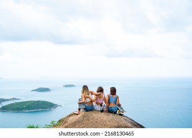 Group Of Asian Woman Skater Sitting On Mountain Peak While Hiking At Tropical Island On Summer Travel Vacation. Female Friends Enjoy Outdoor Activity Adventure Lifestyle And Sport Skating Together