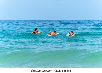 Group Of Asian Woman Surfer Paddling Surfboard And Riding The Wave In The Sea At Tropical Beach In Sunny Day. Female Friends Enjoy Outdoor Activity Exercise And Water Sport Surfing On Summer Vacation