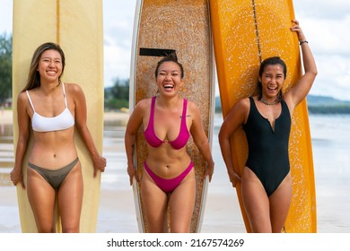 Group Of Asian Woman Surfer In Swimwear Holding Surfboard Walking Together On Tropical Beach At Summer Sunset. Female Friends Enjoy Outdoor Activity Lifestyle Water Sport Surfing On Travel Vacation