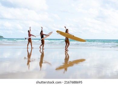 Group Of Asian Woman Surfer In Swimwear Holding Surfboard Walking Together On Tropical Beach At Summer Sunset. Female Friends Enjoy Outdoor Activity Lifestyle Water Sport Surfing On Travel Vacation